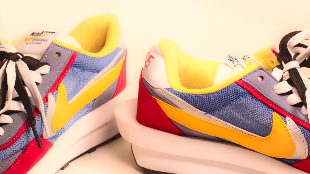 A pair of sneakers with a yellow, blue, and red shoelace