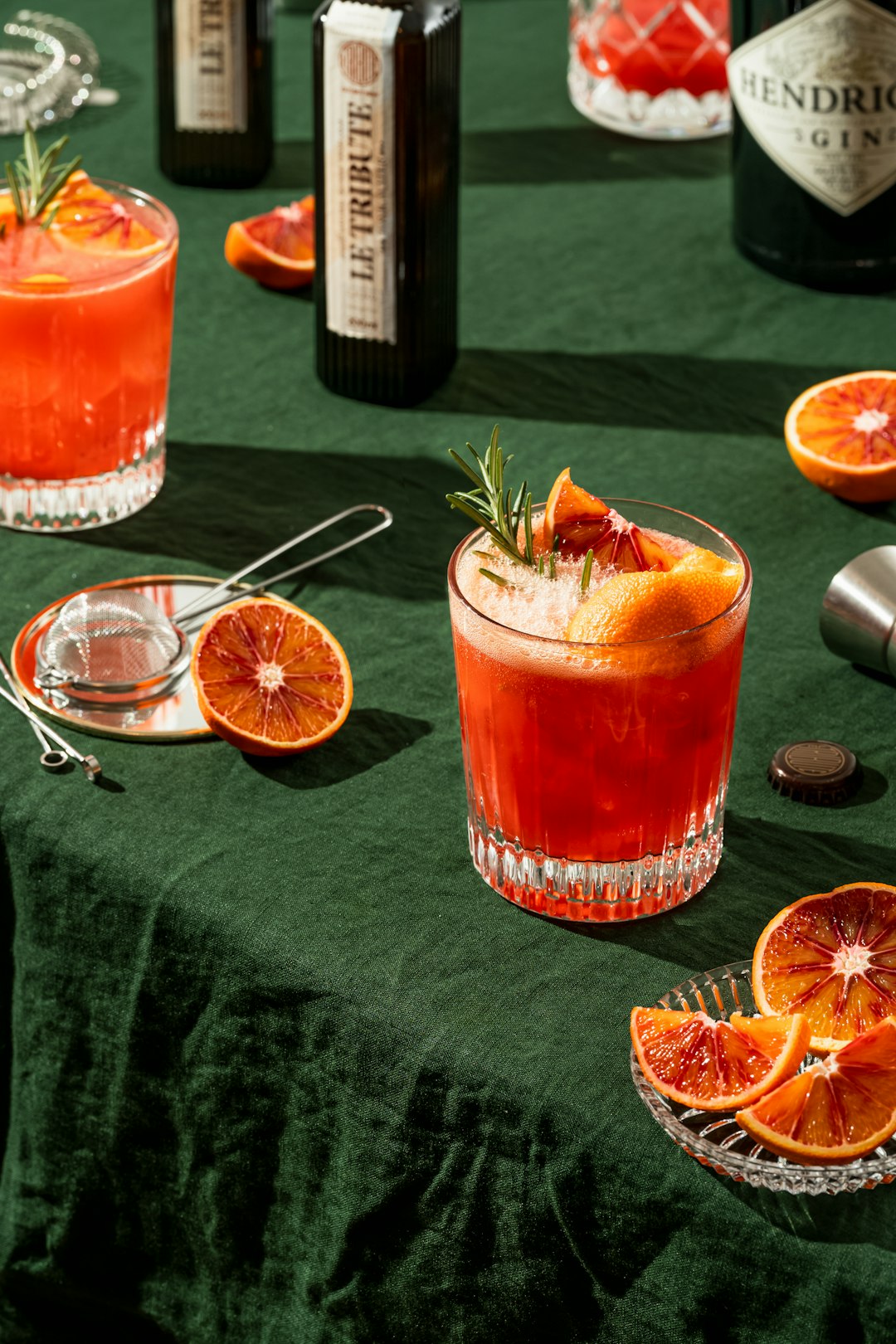 Blood orange cocktails with rosemary sprigs on a dark green linen tablecloth