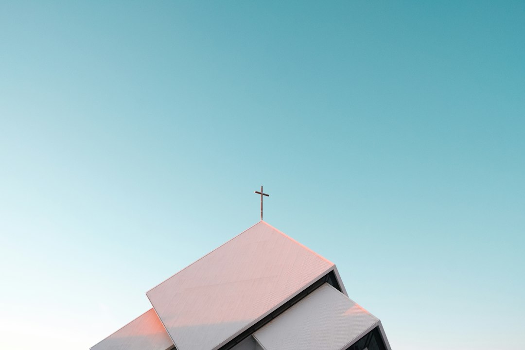 A white church roof with a cross against a clear blue sky