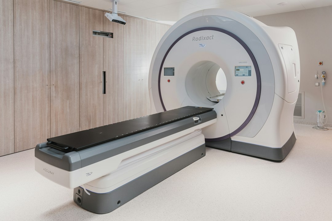 A white medical radiation therapy machine with a black patient table in a clinic