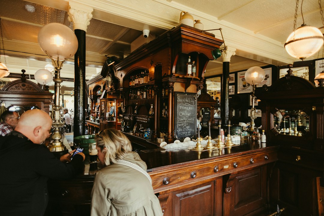Two people at a traditional pub's ornate wooden bar